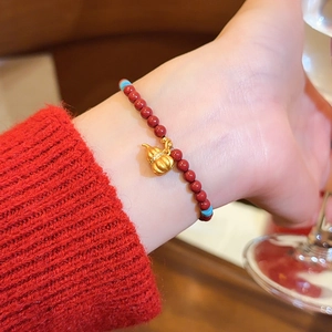 Detailansicht eines roten Achatperlenarmbands mit goldenem Glücksbringer Anhänger