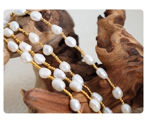 Macro shot of French style baroque freshwater pearls and gold beads on a wooden texture