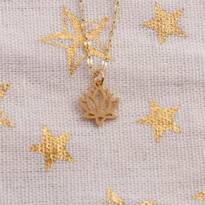 Détail du pendentif fleur de lotus doré ajouré sur une fine chaîne en acier titane