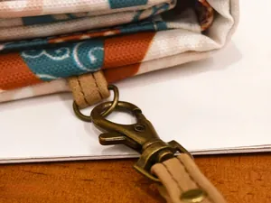 Close-up of retro bronze swivel hook and brown leather strap on patterned fabric