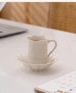 Close-up of ceramic coffee cup with bamboo embossment and petal-shaped edge