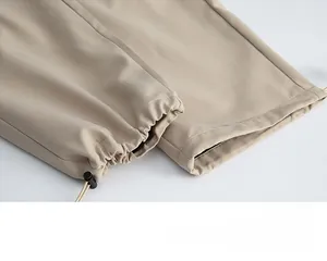 Dettaglio della gamba dei pantaloni cargo kaki con coulisse regolabile e fermo nero