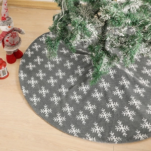 Gray knitted Christmas tree skirt with white snowflake patterns on a wooden floor
