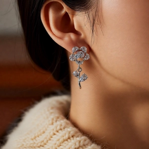 Close-up of flower pendant earrings with zircon stones and silver needles on model