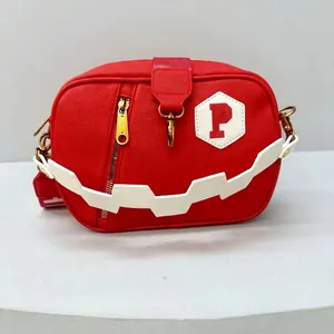 Detail view of red fashion crossbody bag with white zigzag strap and gold metal buckles