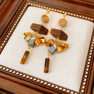 Detail view of retro wood and tiger eye stone tassel earrings on a vintage cushion
