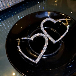 Détail de boucles d'oreilles cœur scintillantes serties de cristaux sur un socle noir