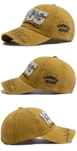 Detail of vintage 1985 embroidery on mustard yellow washed cotton baseball cap with distressed brim