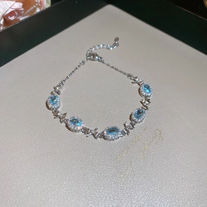 Macro detail of aquamarine zircon bracelet with dragonfly charms and silver accents