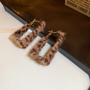 Gros plan détaillé de boucles d'oreilles léopard rectangulaires avec texture douce et crochets dorés