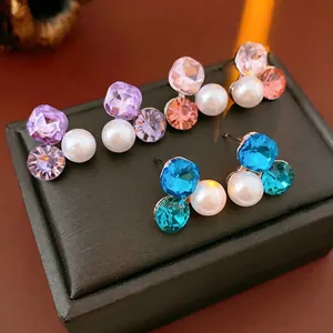 Three pairs of elegant triangle pearl and diamond stud earrings in purple, pink and blue