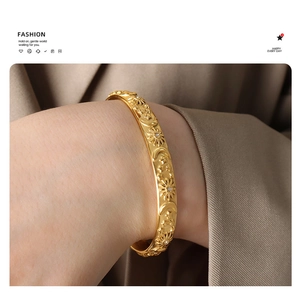 Close-up of gold celestial embossed bangle with sun and moon motifs and sparkling zircons