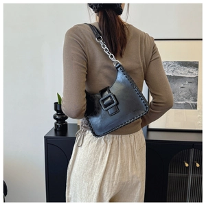 Detail of black shoulder bag featuring chunky silver chain and woven edge craftsmanship