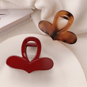 Close-up of heart-shaped hair claws in red and amber resin on a decorative white plate