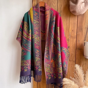 Close-up of ethnic paisley jacquard scarf with tassels on a wooden hanger