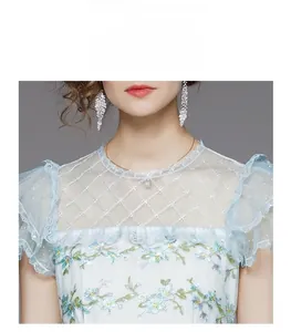 Détail de la robe bleu clair avec broderie florale et encolure en maille blanche