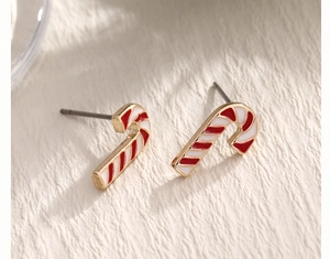 Macro detail of Christmas candy cane earrings with festive red and white enamel stripes