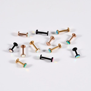 Macro detail of opal labret studs in gold and black finishes with iridescent stones