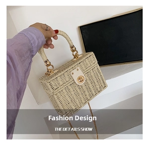 Detail der cremefarbenen Stroh-Box-Tasche mit goldenem Drehverschluss und Metallkette