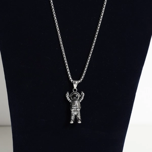 Detailed view of an astronaut pendant in vintage silver steel on a black velvet stand
