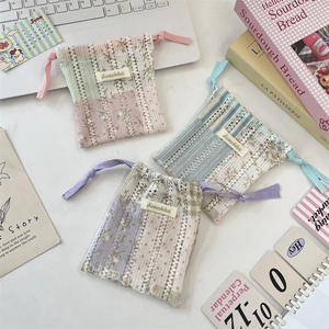 Close-up of three handmade crochet drawstring pouches with floral lining and brand labels