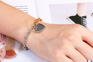 Detail of two-tone heart pendant bracelet with black mirror center on a model's wrist