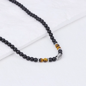 Detailed view of beaded necklace featuring black stones and tiger eye with steel accents