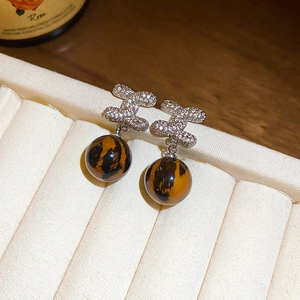 Close-up of H-shaped rhinestone stud earrings with brown leopard print round beads
