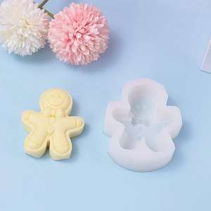 Detailed view of gingerbread man silicone mold and finished beige candle on blue backdrop