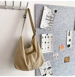 Detail of beige corduroy hobo bag hanging on wall with a cozy aesthetic workspace