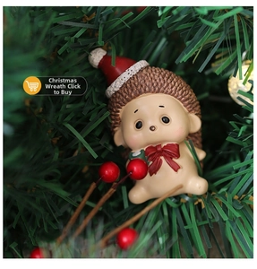 Close-up of cute resin hedgehog ornament wearing a red Santa hat in a festive pine setting