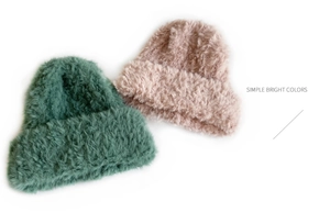 Detailed texture of pink and green plush knit beanies for autumn and winter warmth