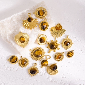 Golden tiger eye stone pendants in sun, heart and oval shapes on textured white stone