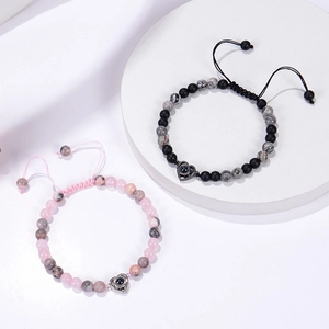Detail of pink and black natural stone couple bracelets with heart projection pendants