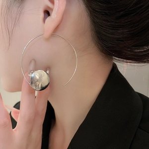 Close-up of asymmetric geometric round hoop earrings with hammered metal finish on model
