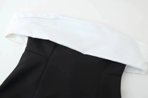 Detailed view of the black and white contrast stitching on the off-shoulder neckline