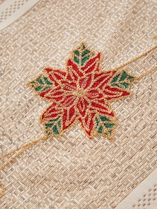 Makroaufnahme von besticktem Weihnachtsstern und Golddetails auf festlichem Spitzenvorhang