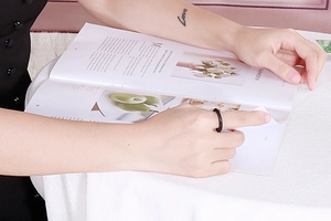 Minimalistischer schwarzer Ring mit Rautenmuster, getragen beim Blättern im Magazin