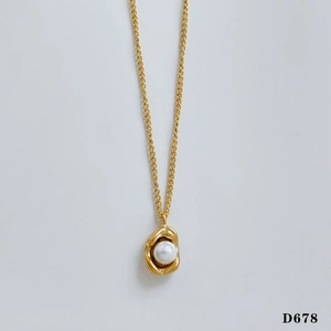 Detailed close-up of a golden geometric pendant with a round white pearl on a fine chain