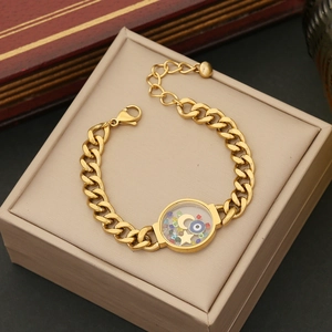Detail of gold Cuban chain bracelet with evil eye and celestial charms on jewelry box