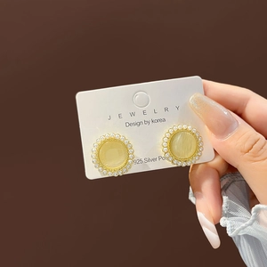 Detail of vintage gold stud earrings with cat-eye stone and small white pearls