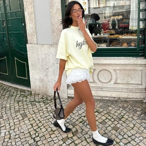 Vista laterale della gonna bianca a balze in pizzo e t-shirt gialla con grafica