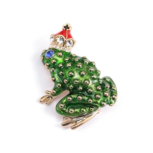 Vintage green enamel frog brooch with gold crown and blue gemstone eyes on white base