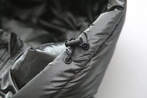 Detail of glossy black puffer jacket featuring adjustable drawstring and high-shine fabric
