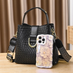Black woven texture bucket bag with striped shoulder strap and phone for size reference
