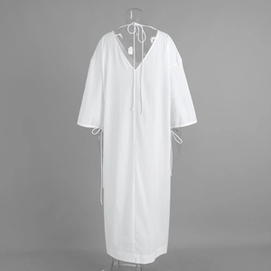 Detail of white cotton dress showing deep V-back design with adjustable tie closures
