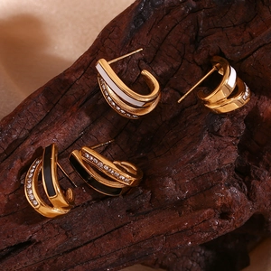 Detail of cross U-shaped earrings with enamel and rhinestones on a rustic wood surface