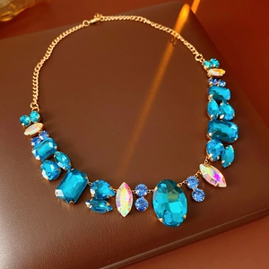 Close-up of golden necklace with sparkling blue crystals and colorful rhinestones