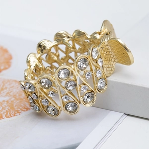 Detail view of a hollow metal hair claw clip with rhinestones on a white table