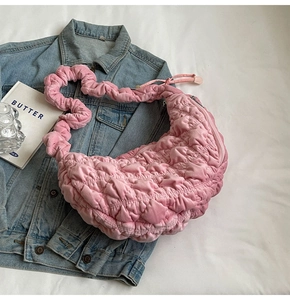 Detail view of pink quilted bubble fabric cloud bag on blue denim jacket surface
